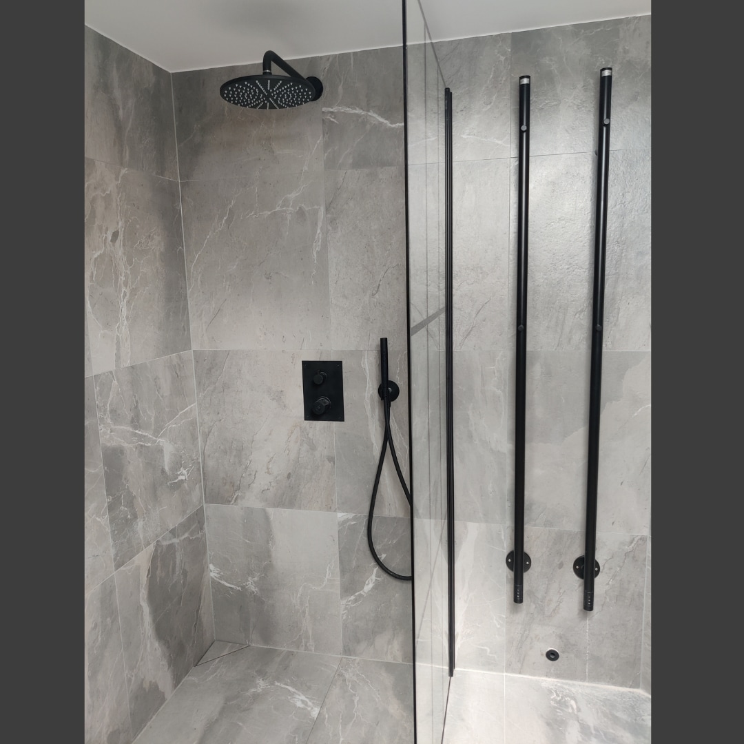grått kakel badrum med svart handdukstork