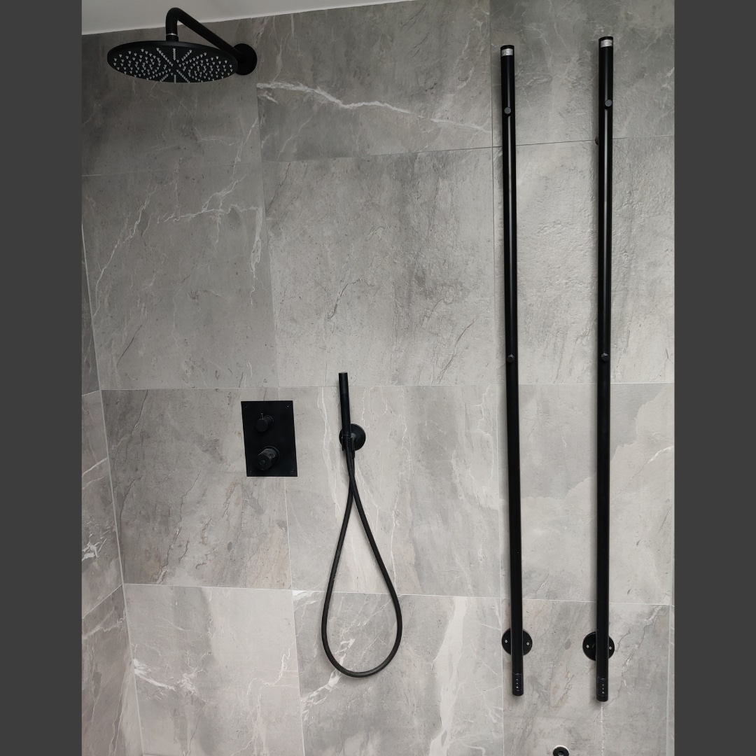 grått kakel badrum med svart handdukstork